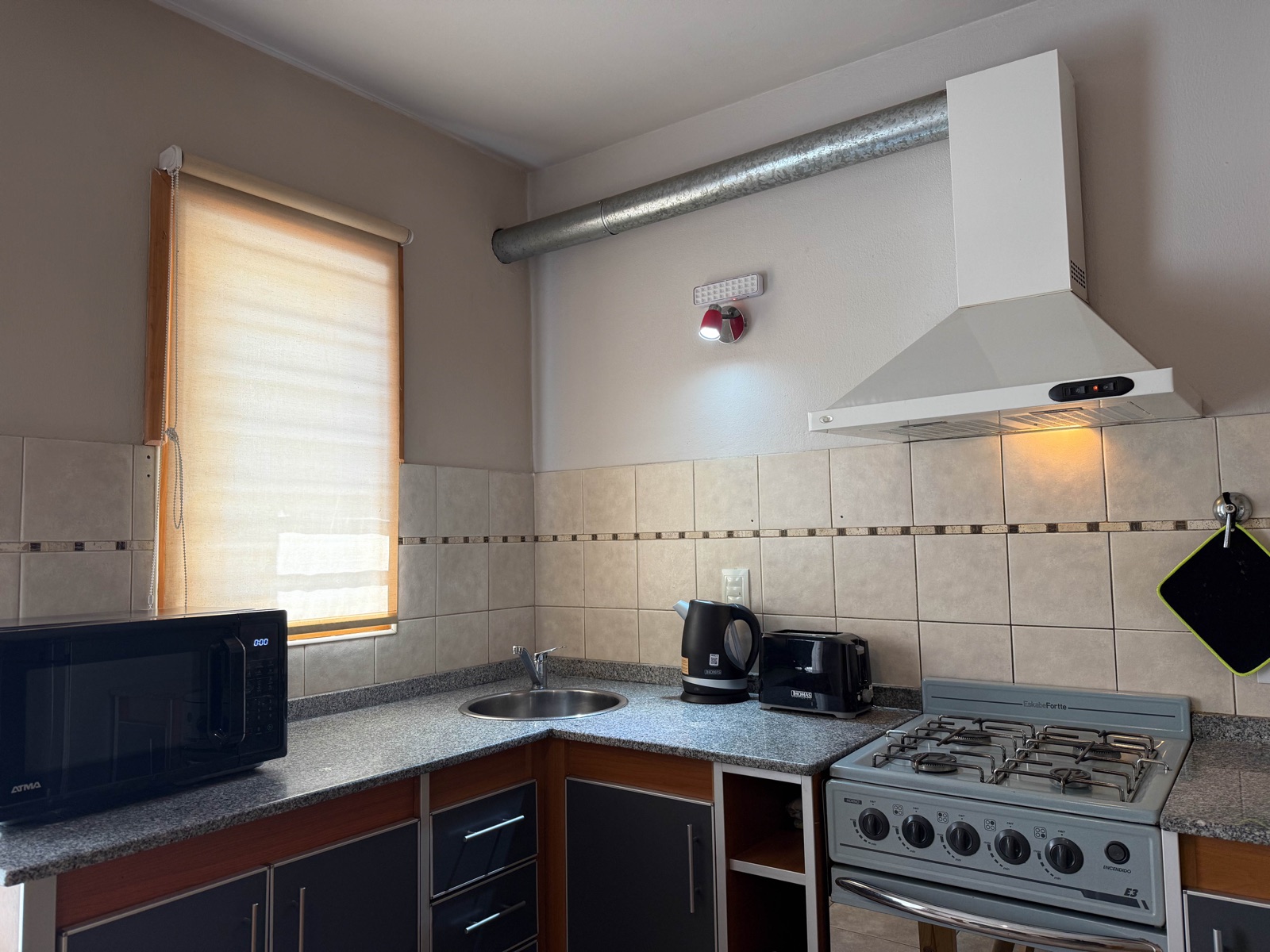 Cocina equipada con microondas, tostadora, cafetera y pava eléctrica